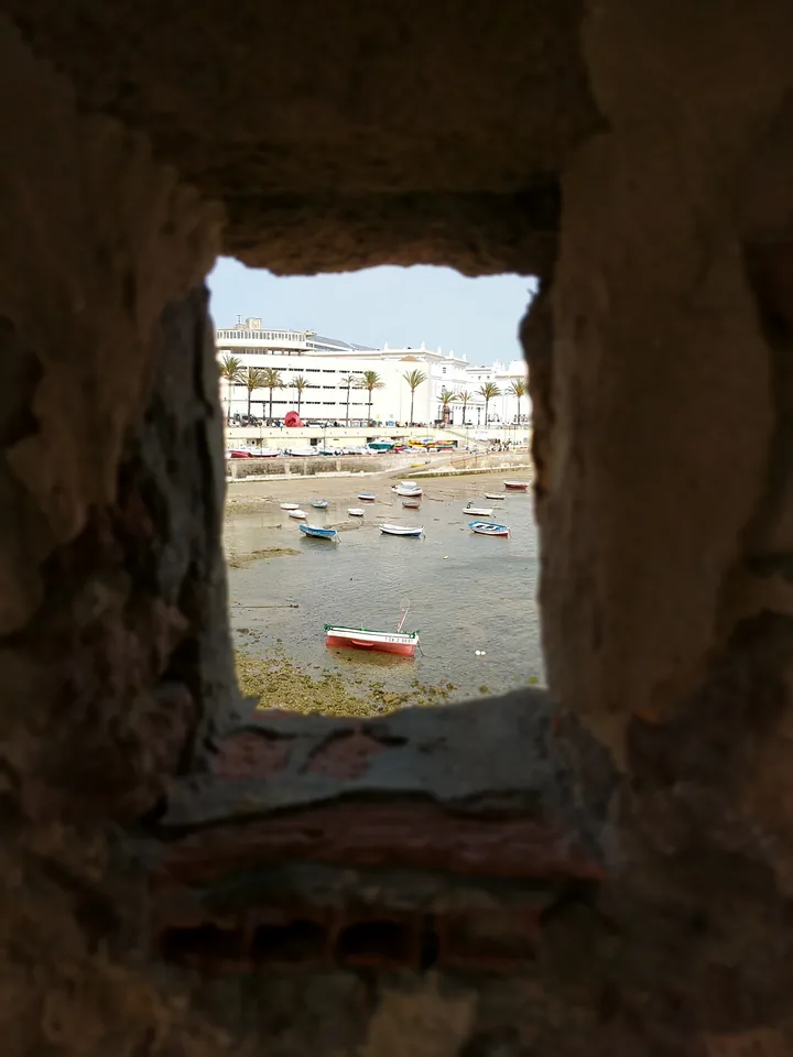 Vista de una plaza a través de una abertura en un muro de piedra