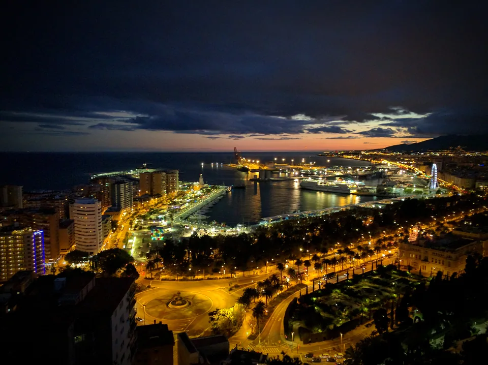 Panorámica nocturna de una ciudad costera y su puerto iluminado