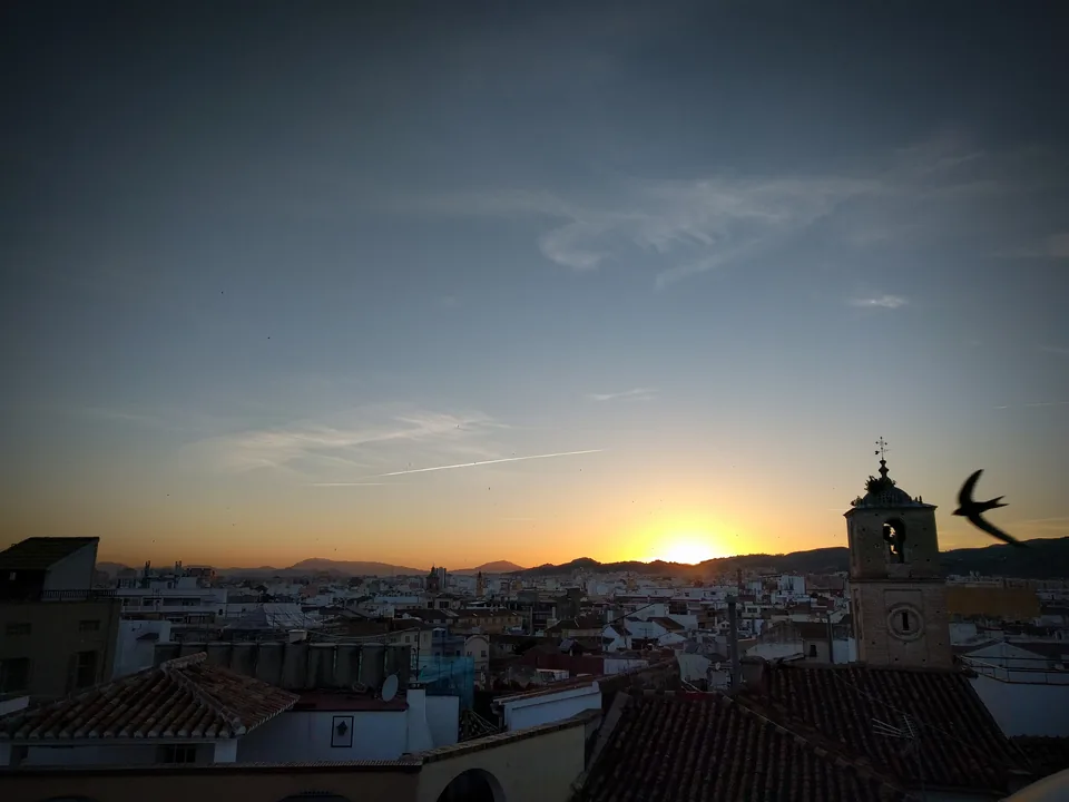 Sol poniéndose sobre los tejados de una ciudad