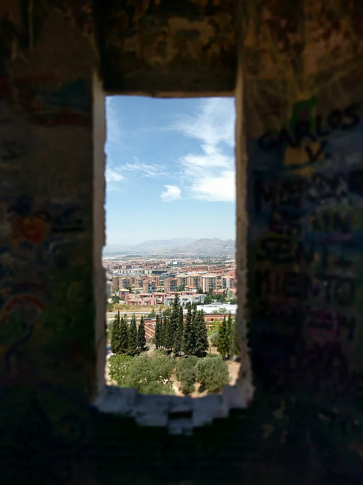 Paisaje urbano visto a través de una ventana en un muro de piedra