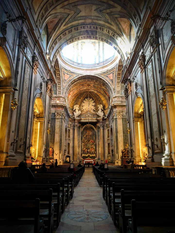 Interior de una iglesia con una cúpula luminosa y bancos de madera