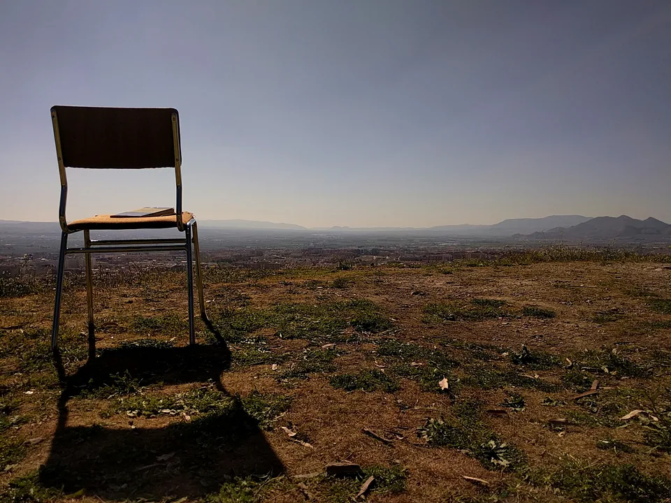 Silla sobre un terreno de hierba seca con montañas al fondo