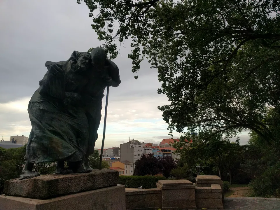 Escultura de piedra bajo un árbol con la ciudad al fondo