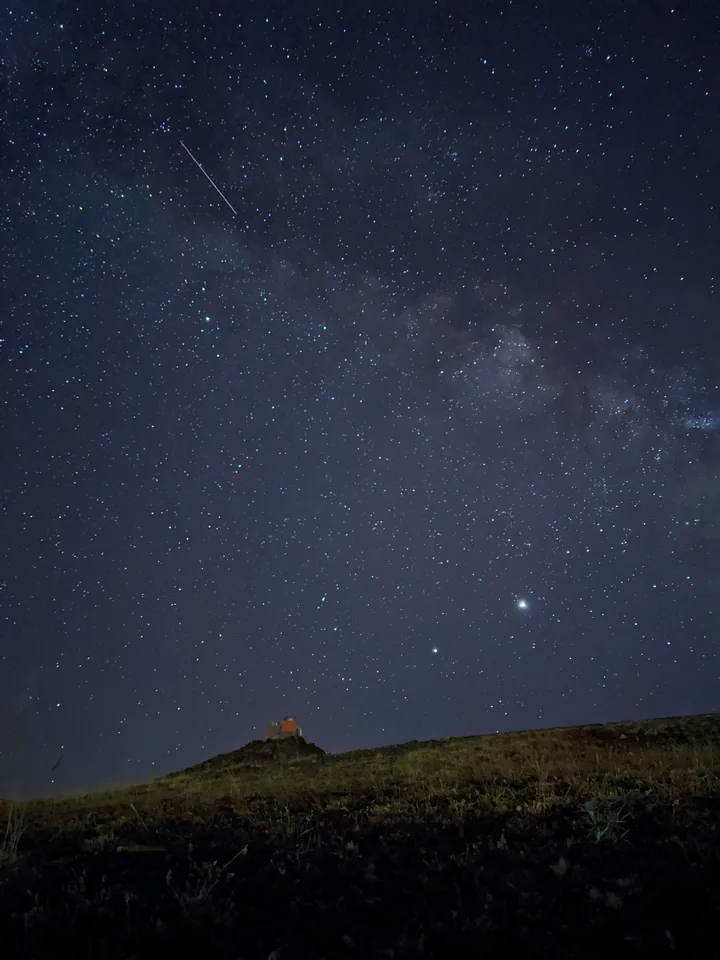 Cielo estrellado sobre la silueta oscura de una colina