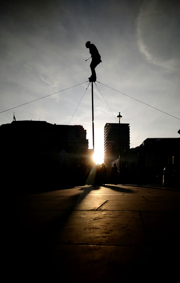 Escultura en silueta frente al sol entre edificios