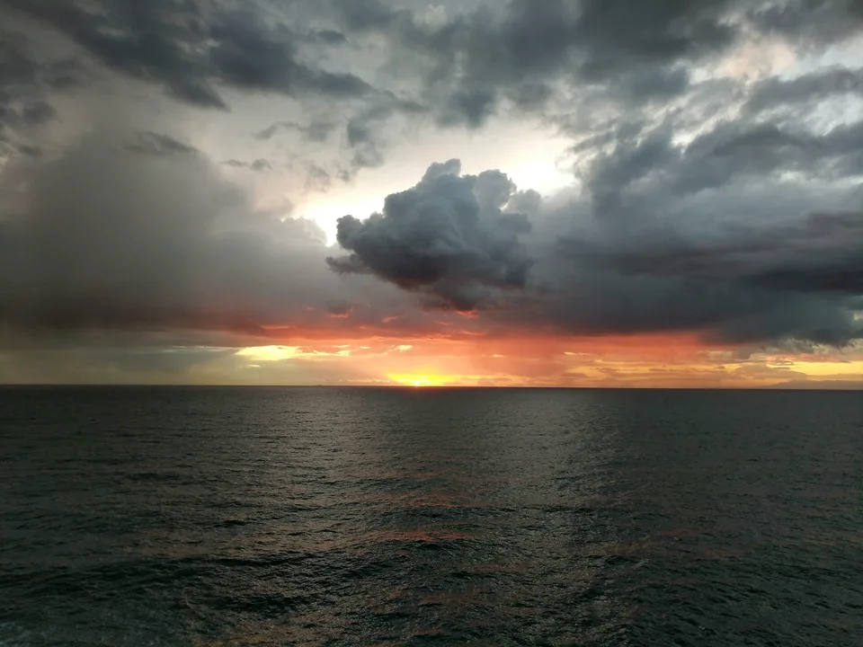 Nubes oscuras sobre el mar y una franja de luz al atardecer