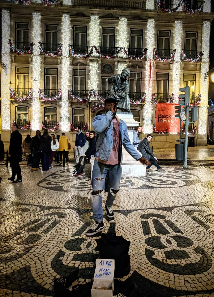 Personas caminando bajo arcadas sobre un pavimento de mosaico