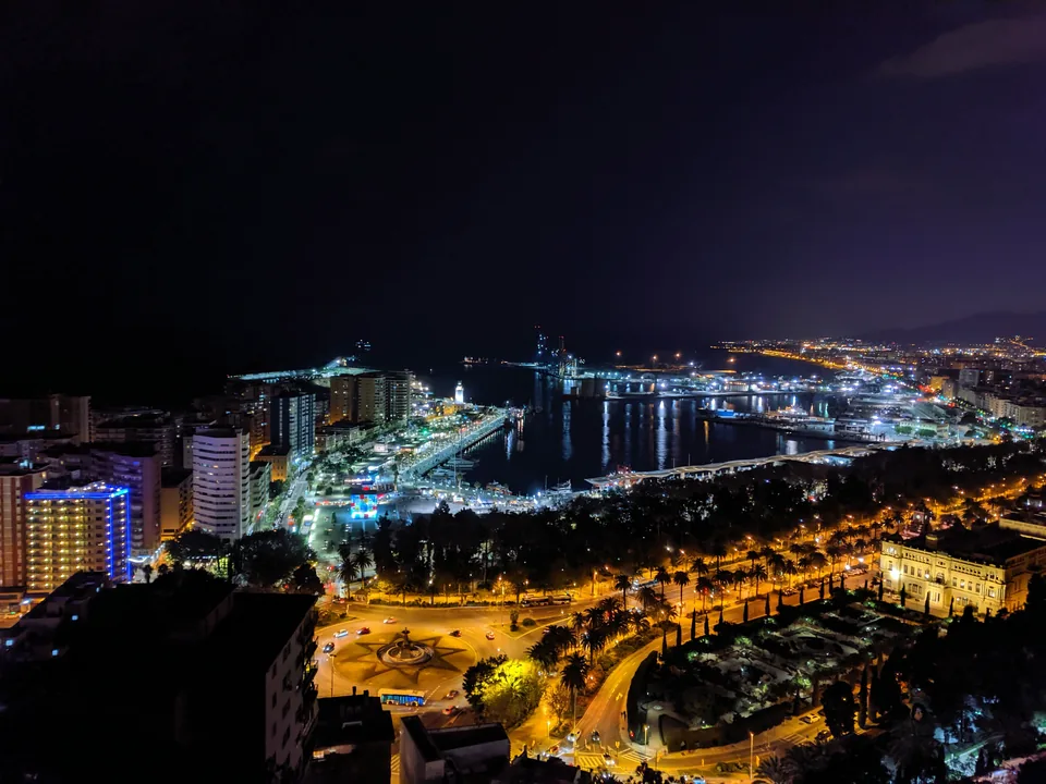 Ciudad costera y puerto iluminados bajo un cielo nocturno