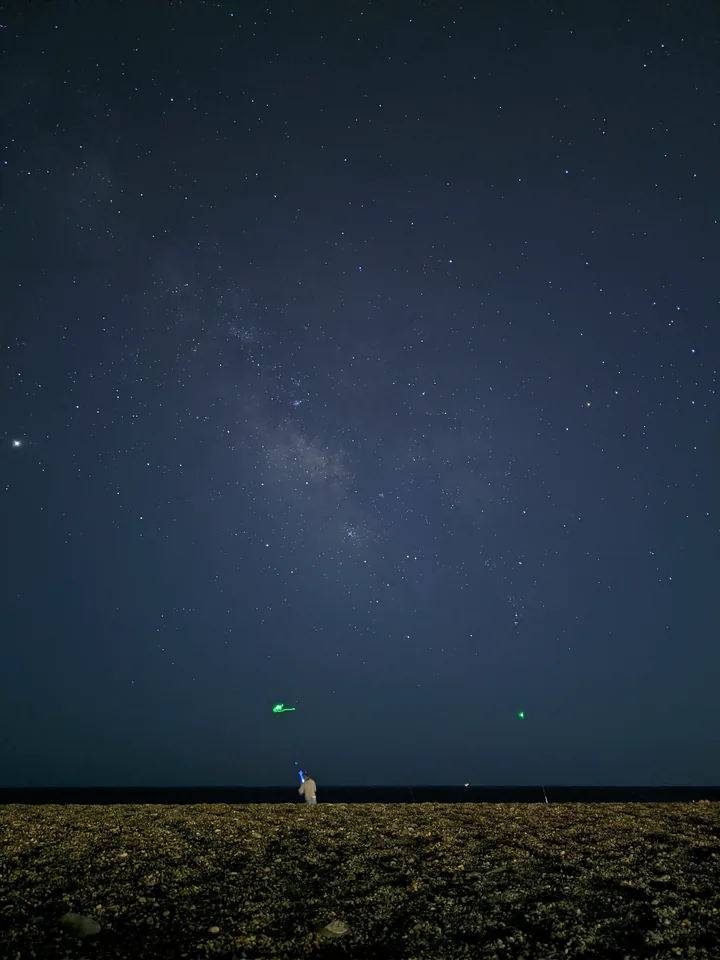 Cielo estrellado sobre un campo con una pequeña figura iluminada