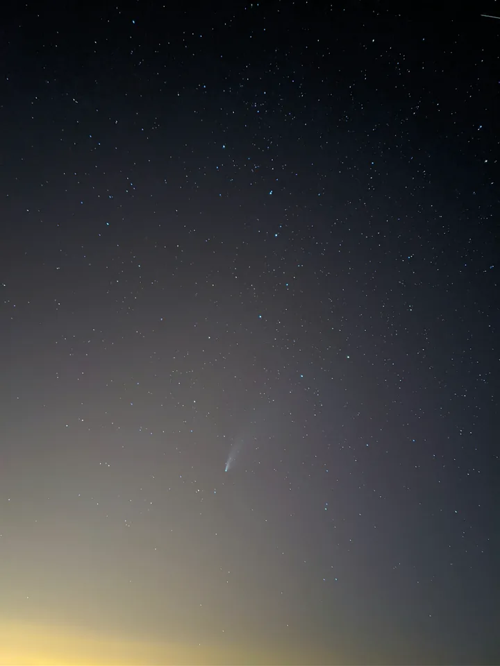 Cielo nocturno con estrellas y luz tenue cerca del horizonte